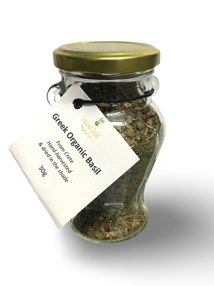 A glass jar containing dried Greek basil leaves, with a label that reads 'Greek Organic Basil'.