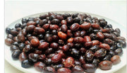 Whole organic Kalamata olives in sea salt brine, on a plate, with stone in