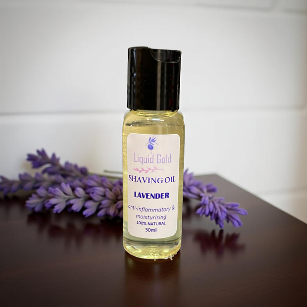 Bottle of lavender shaving oil with lavender flowers on a wooden surface